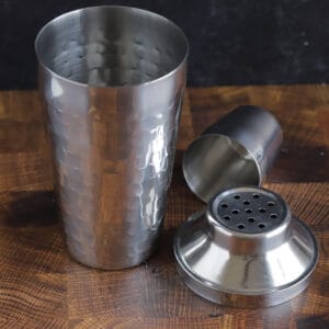 a beaten metal cocktail shaker and strainer