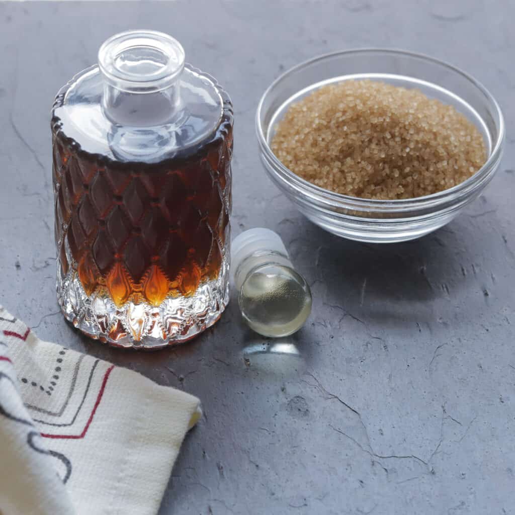 Dark brown syrup with a bowl of Demerara sugar