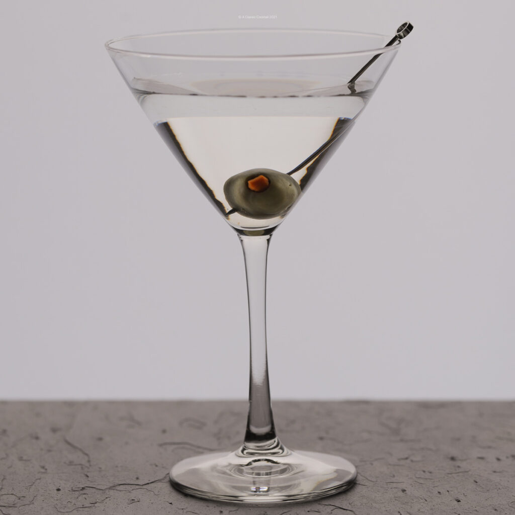 A classic martini mixed with vodka in a cocktail glass and olive